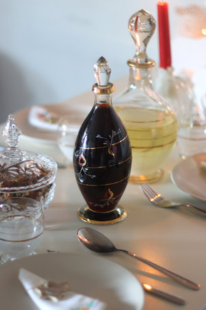 Table set for Christmas meal, with plates, wine, decorations and lit candles. Selective focus.の写真素材