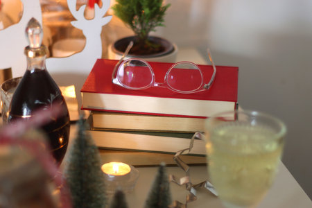 Books, lit candles and Christmas decorations on the table. Cozy Christmas hygge at home. Selective focus.の写真素材