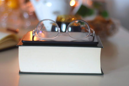 Reading glasses on top of a book. Hygge at home. Selective focus.の写真素材