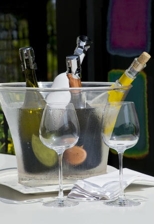 Served white wine with two empty glasses on a sunny bar tableの写真素材