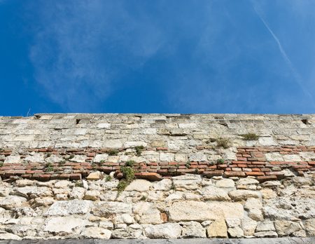 Ancient stone and brick wall under the clear blue summer skyの写真素材