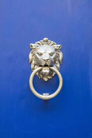 Lion head door knocker on a blue painted wooden backgroundの写真素材