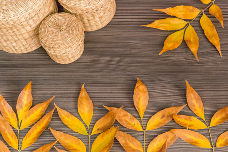 Yellow leaves and baskets arranged on a wooden surface, concept of autumn backgroundの写真素材