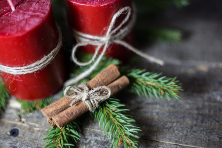 Winter background with fir branches, candles and cinnamon sticks on wooden board. Christmas and New Year greeting card.の写真素材