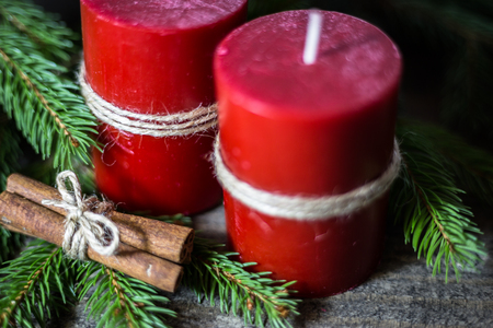 Winter background with fir branches, candles and cinnamon sticks on wooden board. Christmas and New Year greeting card.の写真素材