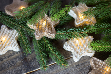 Christmas card with light star garland and fir branches oh the old wooden background. Empty space for text. Winter holidays concept.の写真素材
