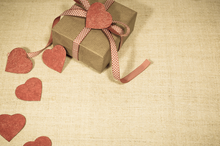 Gift box with red ribbon and hearts in vintage style. Valentine's day greeting card with place for text.の写真素材