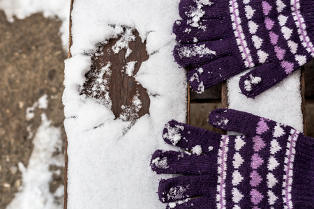 Heart drawn in the snow on a wooden bench and winter gloves. Valentine's background concept.の写真素材