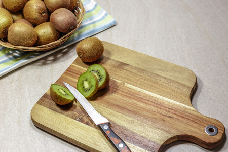 Ripe whole kiwi fruits and slices on a cutting board with an old knife, prepares detox smoothie.の写真素材
