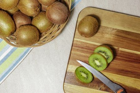 Ripe whole kiwi fruits and slices on a cutting board with an old knife, prepares detox smoothie.の写真素材