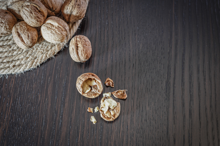 Top view of walnut kernels and whole walnuts on a dark wooden table, space for text. Healthy food concept.の写真素材