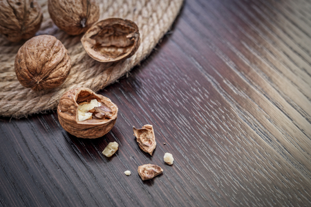 Close-up view of walnut kernels and whole walnuts scattered on a dark wooden table, selective focus and space for text. Healthy food concept.の写真素材