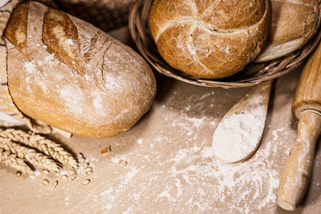 Close-up view of two different kind of freshly baked bread on a rustic background with wheat and flour. Bakery and grocery concept.の写真素材
