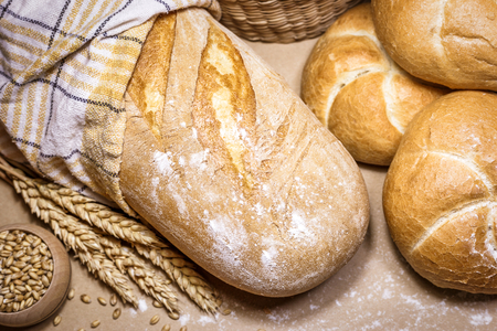 Close-up view of two different kind of freshly baked bread on a rustic background with wheat and flour. Bakery and grocery concept.の写真素材