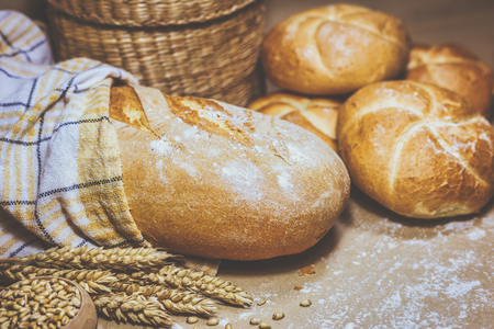 Close-up view of two different kind of freshly baked bread on a rustic background with wheat and flour. Bakery and grocery concept. Photo in retro style.の写真素材