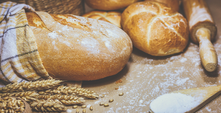 Close-up view of freshly baked bread on a rustic background with wheat and flour. Bakery and grocery concept. Photo in retro style.の写真素材