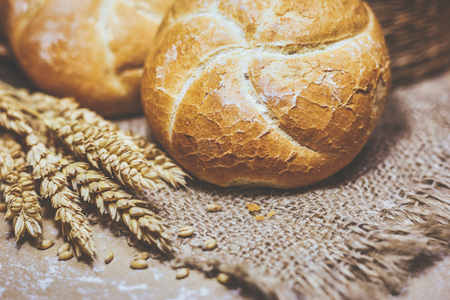 Close-up view of freshly baked bread on a rustic background with wheat and flour. Bakery and grocery...