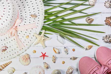Tropical palm leaves, summer shoes, hat, starfish and shells on white wooden table, top view. Summer relaxation backgroundの写真素材
