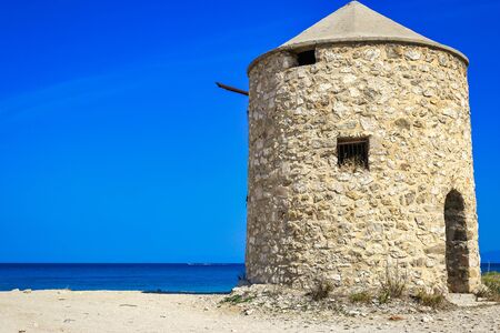 Beautiful seascape with old windmill on Agios Ioannis (Gyra) beach, Lefkada island, Greeceの写真素材