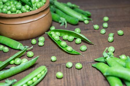 Fresh green peas and pods on rustic wooden background, close-up with soft focus. Concept of healthy eating, fresh vegetables.の写真素材
