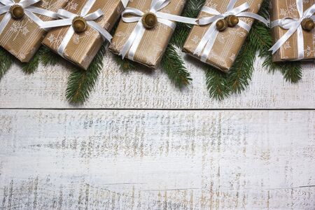 Christmas gifts boxes with pine branches on light wooden background, top view with copy space.