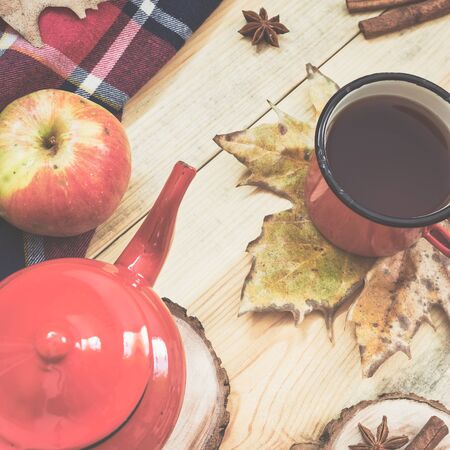 Hot tea, warm blanket, apple, cinnamon sticks, anise star and autumn leaves on old wooden background, vintage toned photo. Top view, flat lay.の写真素材