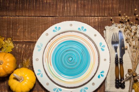 Rustic table setting for Thanksgiving diner with autumn leaves, acorns and pumpkins for decoration. Top view with copy space.の写真素材