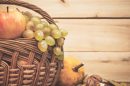 Autumn still life with fruits, pumpkins, rose hips and nuts on wooden table, copy space. Vintage toned photo.の写真素材