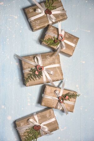 Christmas gifts wrapped in craft paper on textured light blue background. Holiday and celebration...