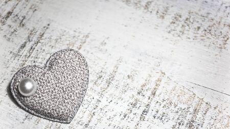 Fabric heart with a pearl on a white woodenの写真素材