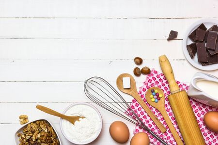 Ingredients and utensils for baking cakes. Eggs, flour, milk, sugar, nuts and chocolate on white...