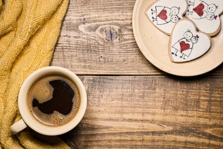 Cup of coffee and heart shaped cookies on rustic wooden background. Top view with copy space.