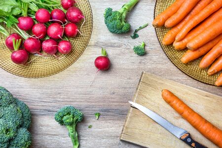 Fresh organic red radishes, carrots and broccoli on wooden background. Top view with copy space. Healthy nutrition concept.の写真素材