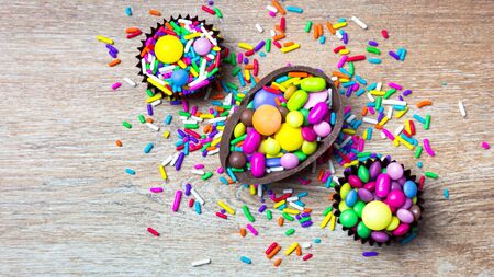 Mixed colorful candies and chocolate eggs over wooden background. Top view with copy space.の写真素材