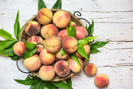 Ripe red peaches in a basket on a rustic white table, top view. Healthy organic fruit.の写真素材