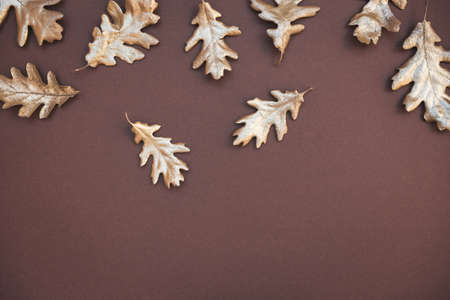 Autumn composition. Pattern made of autumn golden colored leaves on dark brown background. Flat lay,...