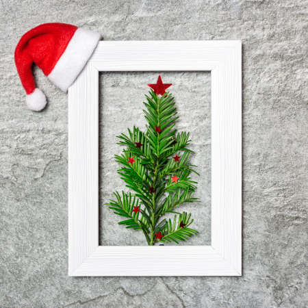 Minimalist Christmas tree made of evergreen plant in white photo frame. Creative flat lay...