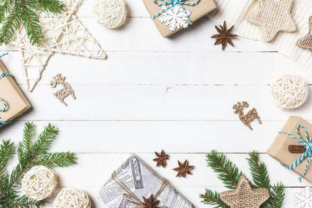 Christmas or winter composition. Christmas gifts, fir tree branches, knitted blanket and ornaments on white wooden background. Flat lay, top view, copy space.の写真素材