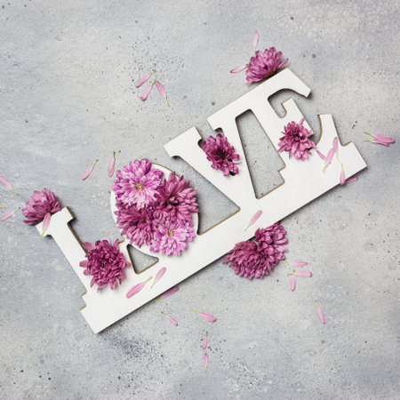 Floral Greeting card. Creative layout made of colorful flowers and word LOVE on gray stone background. Love concept. Flat lay.の写真素材