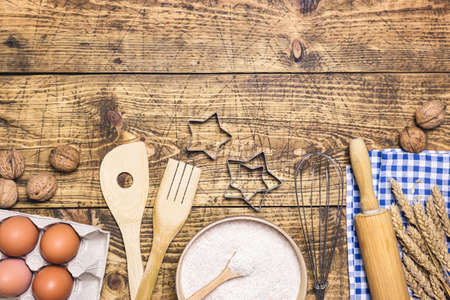 Frame of baking and cooking pastry or cake with ingredients and utensils. Eggs, nuts, flour and wheat on rustic wooden background with copy space for text, flat lay.の写真素材