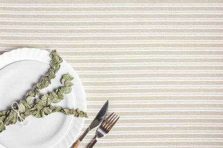 Festive table setting with white plate, cutlery and eucalyptus branches. Beautiful flat lay arrangement.の写真素材