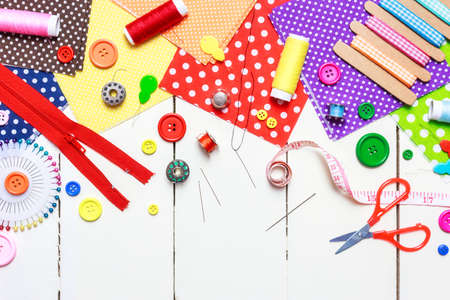 Various fabric, tools and accessories for sewing on a light wooden background. Top view, copy space.の写真素材