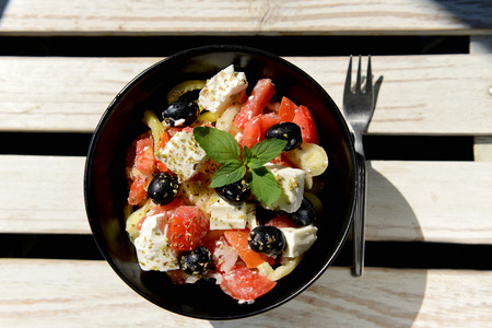 Fresh mixed vegetables salad with cheese on white wooden tableの写真素材