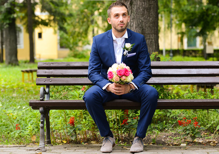 Groom waiting for bride and holding bouquetの写真素材