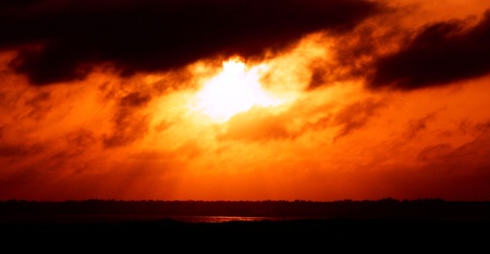 The sun setting below the clouds.の写真素材