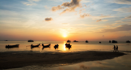 Beautiful silhouette of couple walking on the beach.の写真素材