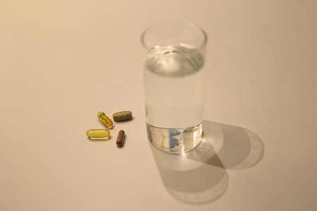 Many kinds of medicine and cup of water on the white table, nutritional supplement on the table