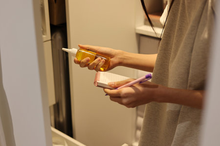 Woman is holding cosmetic bottle and notebook, worker is taking inventory in a warehouseの写真素材