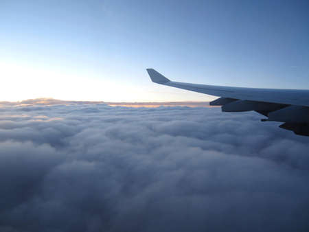 Airplane wing during flight above the clouds. Clear sky in the distance