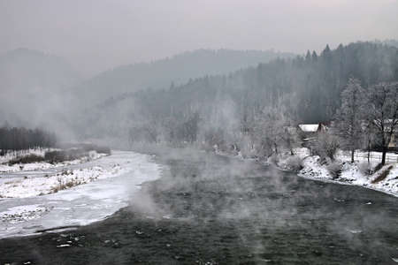 Steaming mountain river. Dunajec in the Pieniny on a frosty, gloomy day. Kroscienko on the Dunajec River. Polish mountains in winterの写真素材